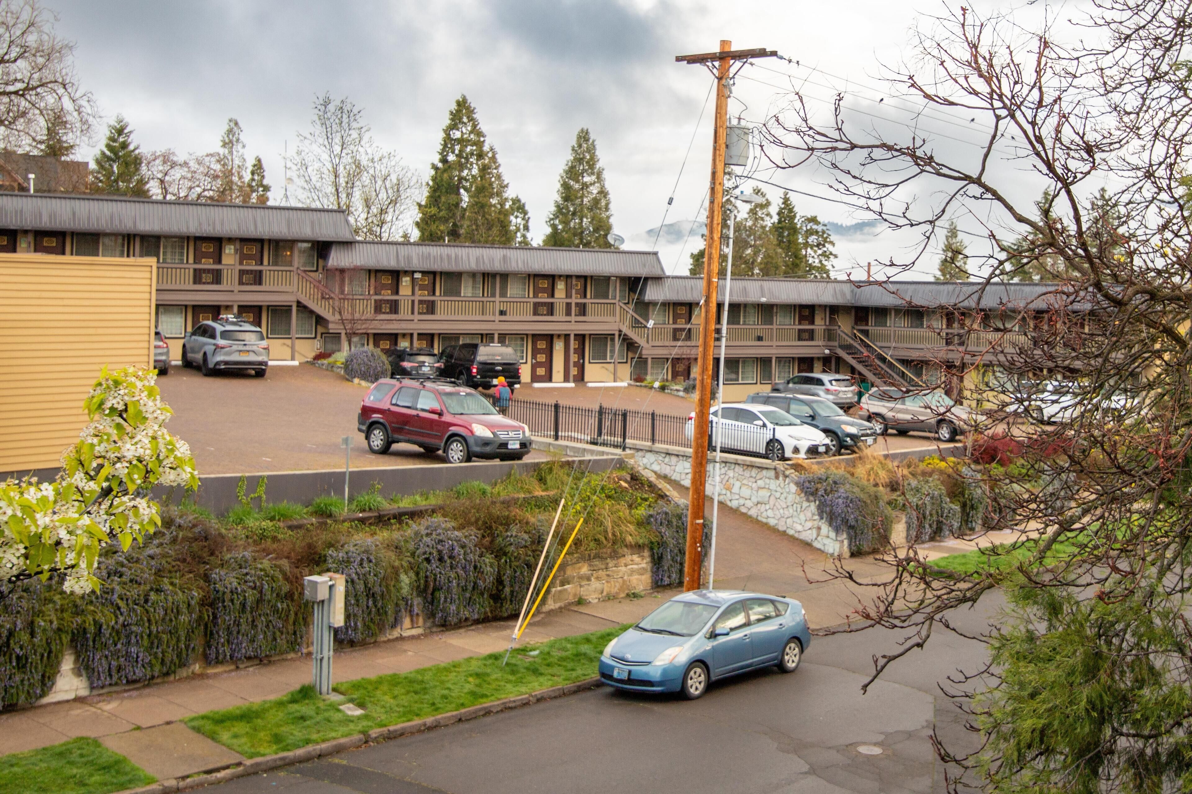Un motel con edificios de varios pisos, un estacionamiento y un pequeño jardín.