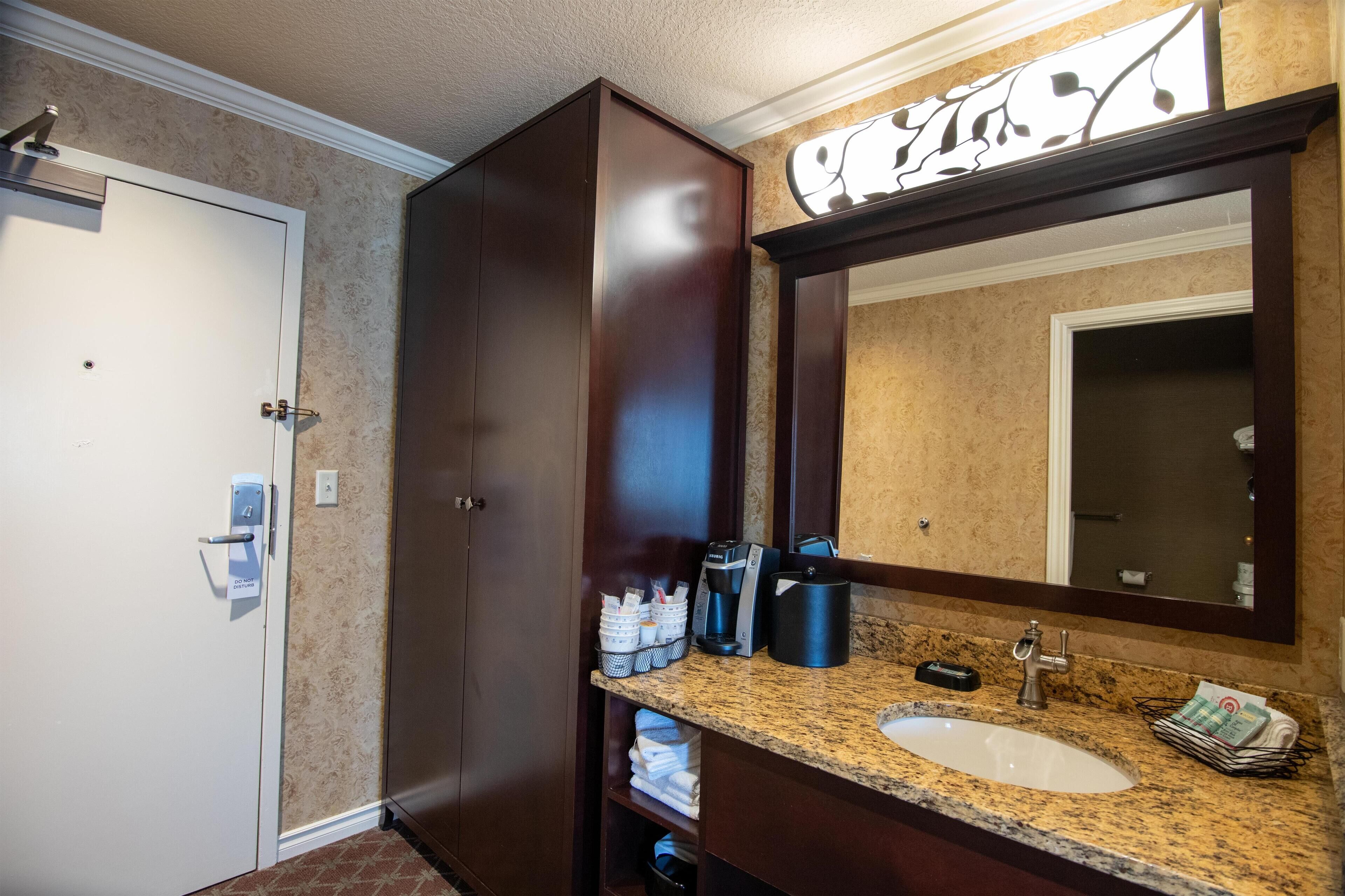 A bathroom with a sink, mirror, and dark wooden cabinets.