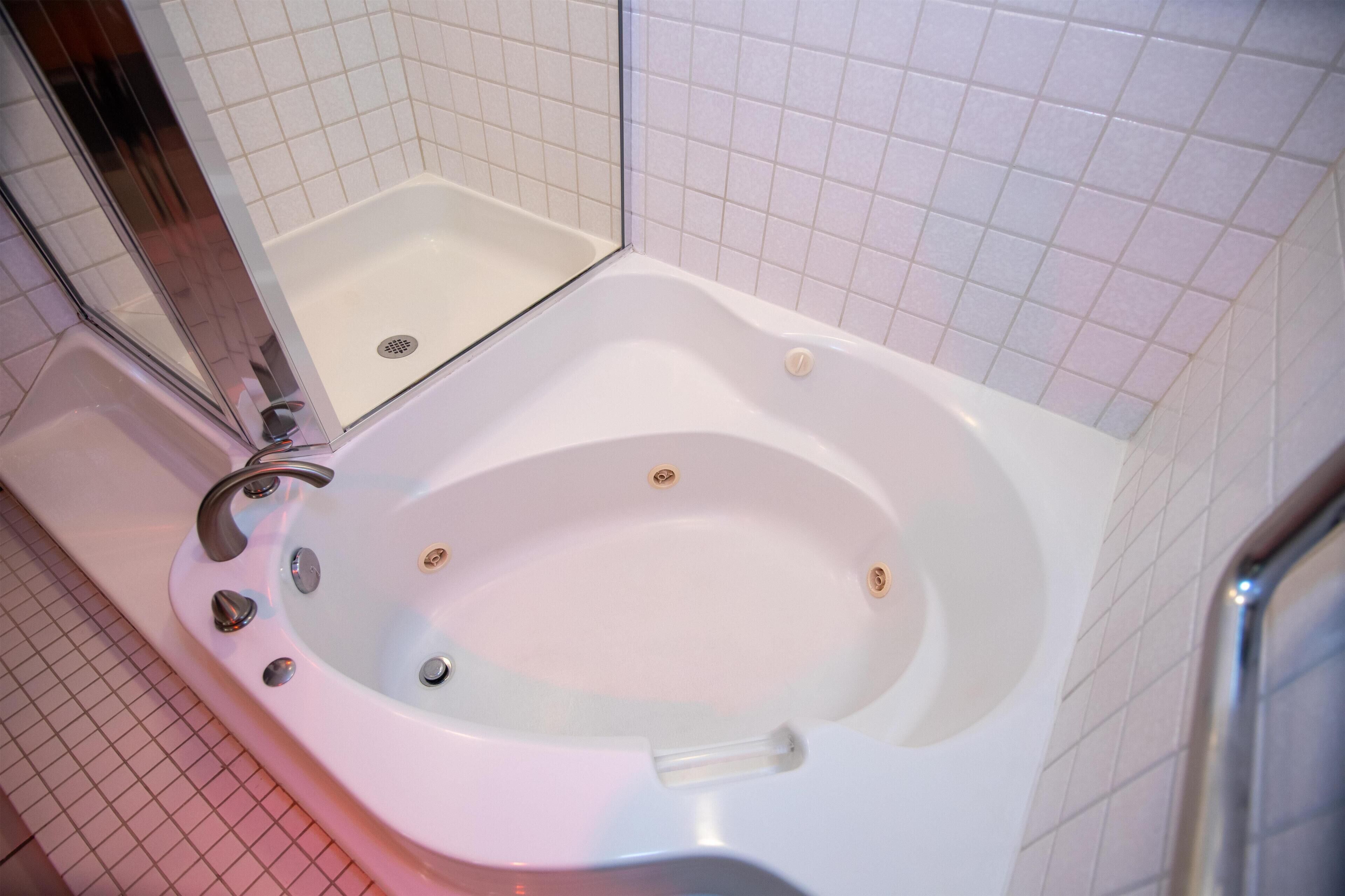 Une salle de bain avec une baignoire blanche, des murs carrelés et un espace douche.