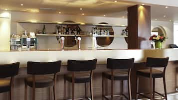 Een bar met krukken, een toog en een assortiment flessen en glazen.