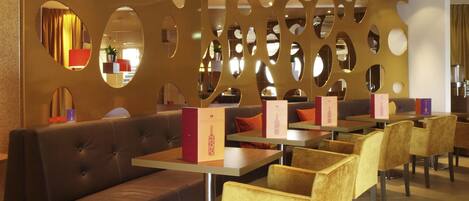 A restaurant interior with a curved wall, multiple seating areas, and tables.