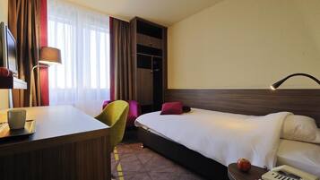 Een hotelkamer met een bed, bureau, stoel, lamp en telefoon.