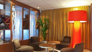 A modern lounge area with round seating, a central table, and a large floor lamp.