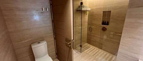 A modern bathroom with a toilet, a glass shower enclosure, and a towel rack.