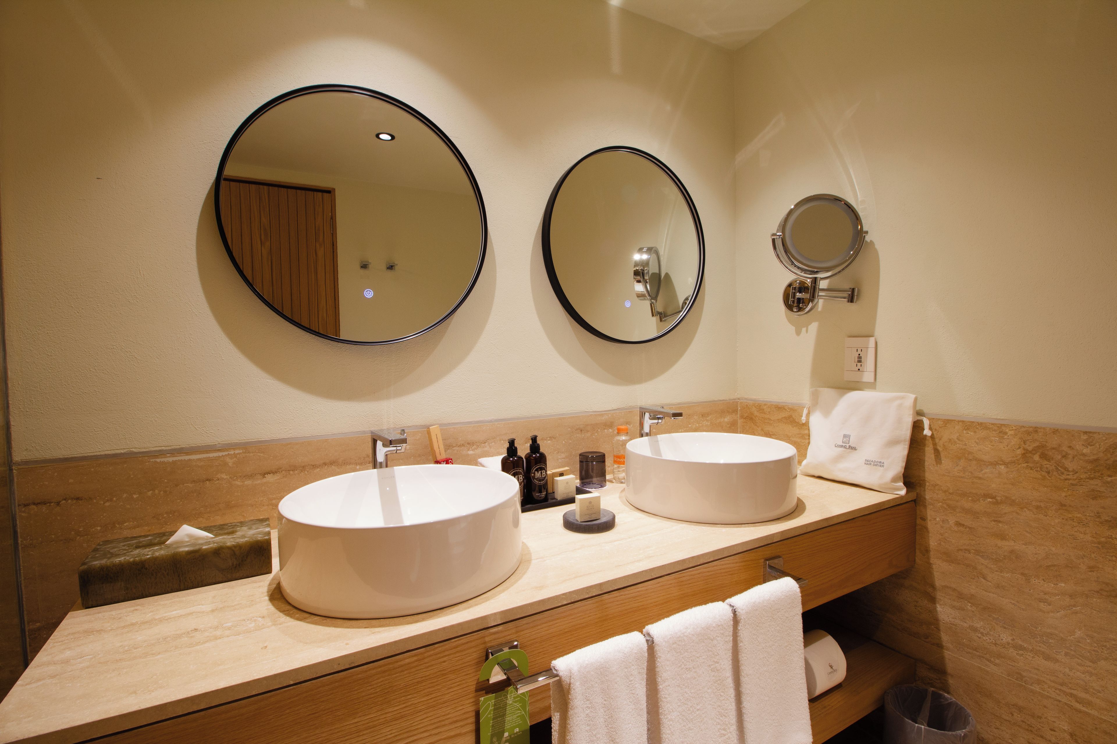 Een badkamer met twee wasbakken, een spiegel en toiletartikelen.