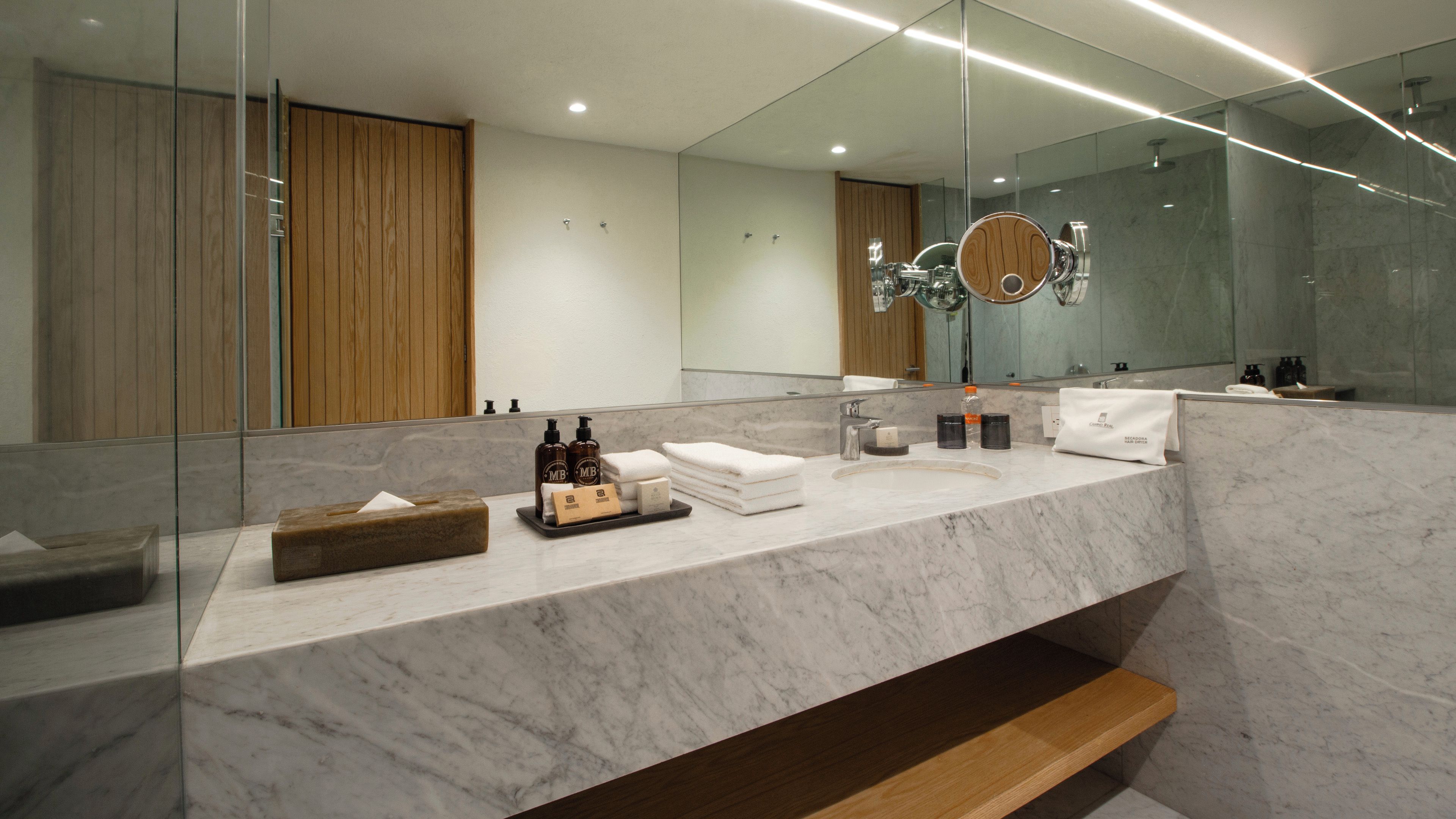 Une salle de bain moderne avec un comptoir en marbre, un meuble-lavabo en bois et un grand miroir.