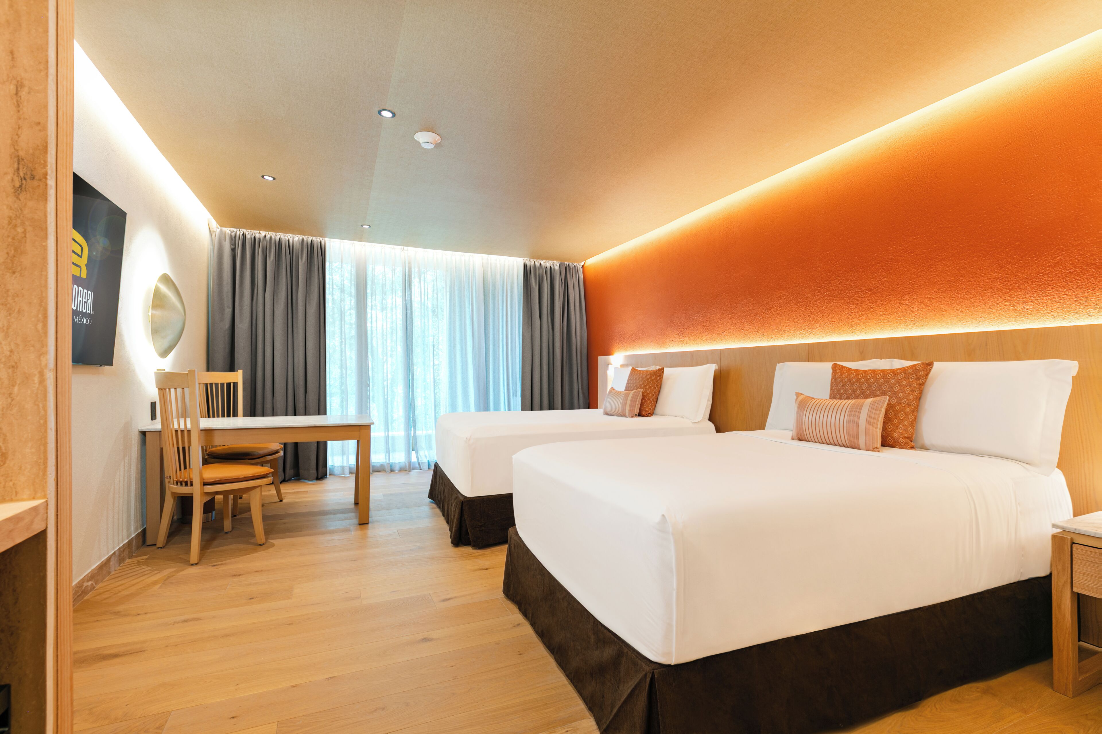 A hotel room with two beds, a desk, and a chair.