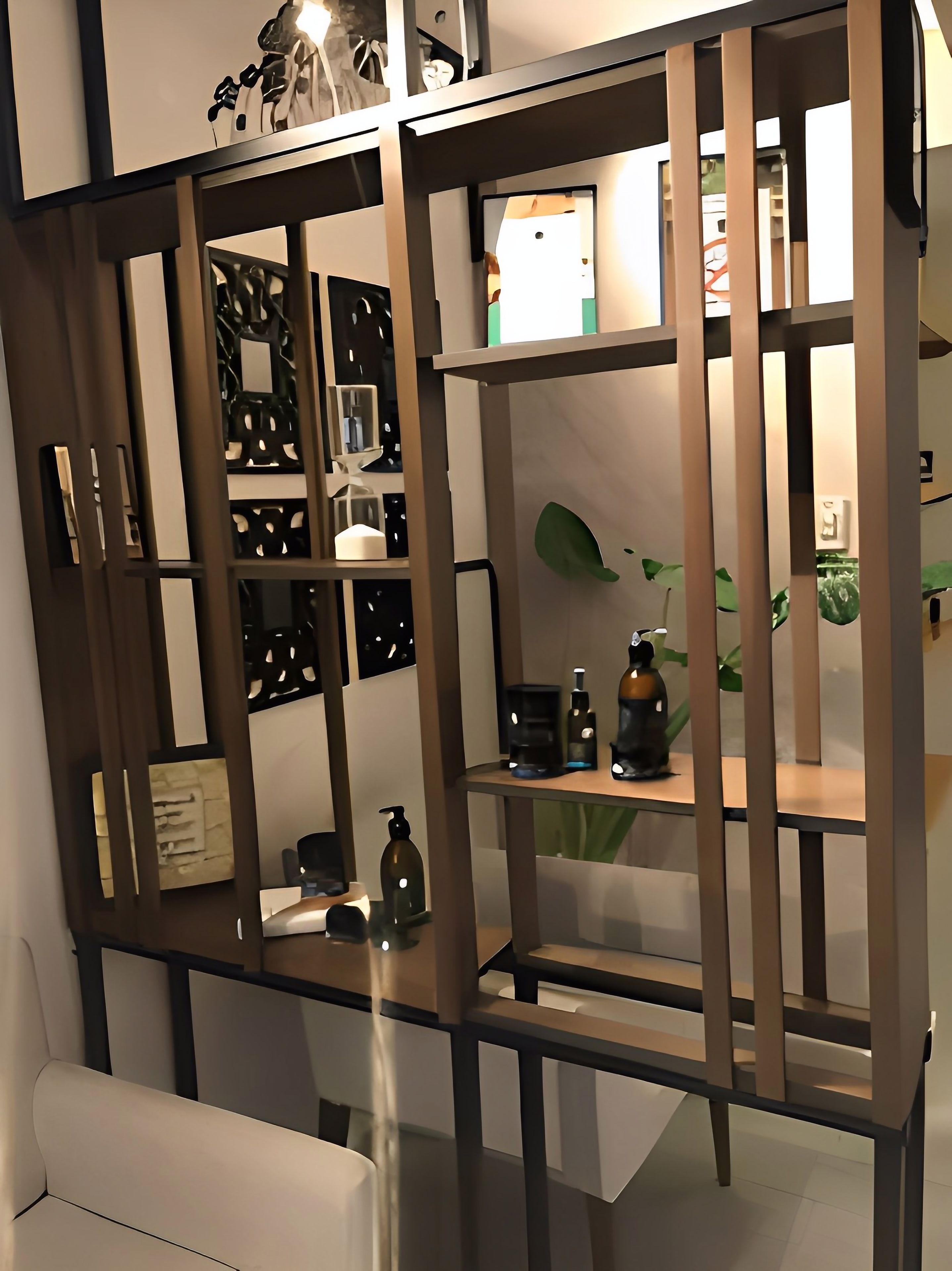 Een modern interieur met een houten scheidingswand, planken met diverse objecten en een witte bank.