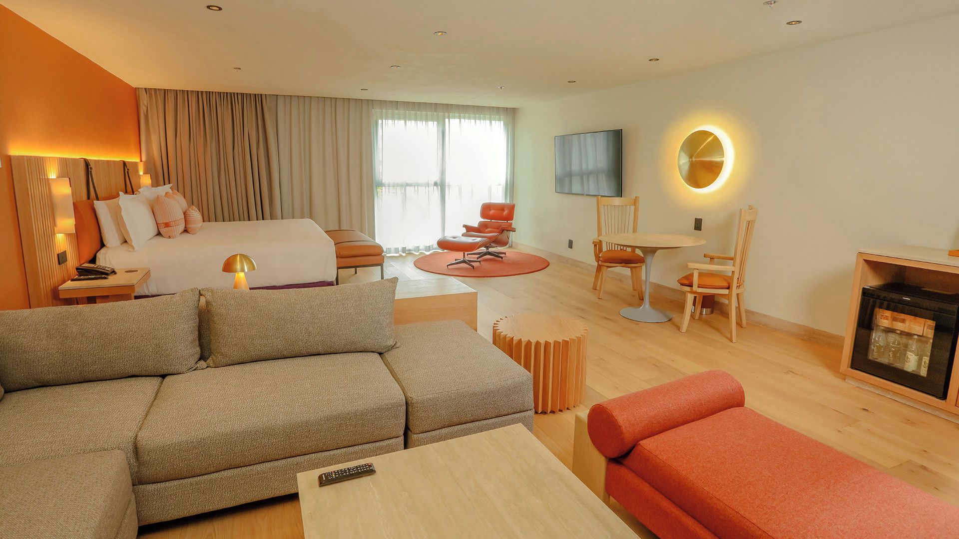 Habitación de hotel con cama, sofá, mesa de centro, televisor, chimenea y zona de comedor con sillas y mesa.