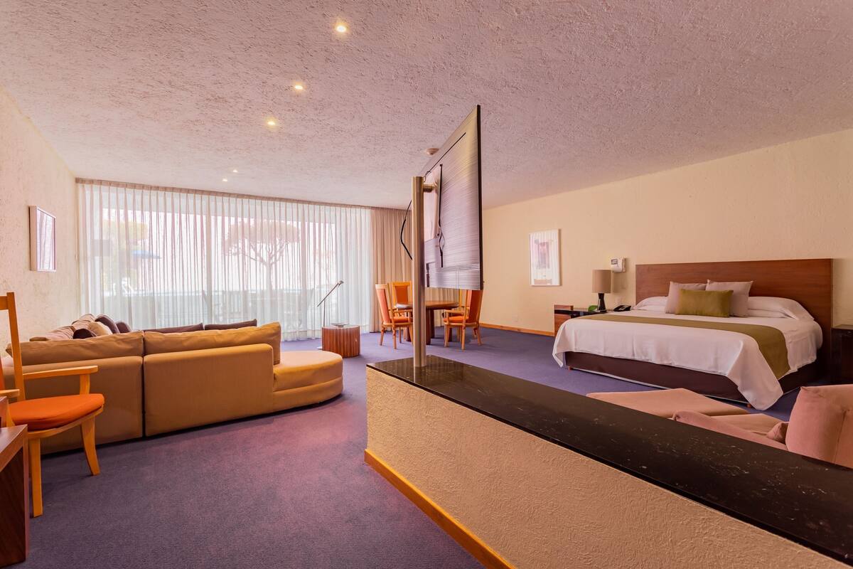 A hotel room with a sofa, a bed, a desk, and a chair.