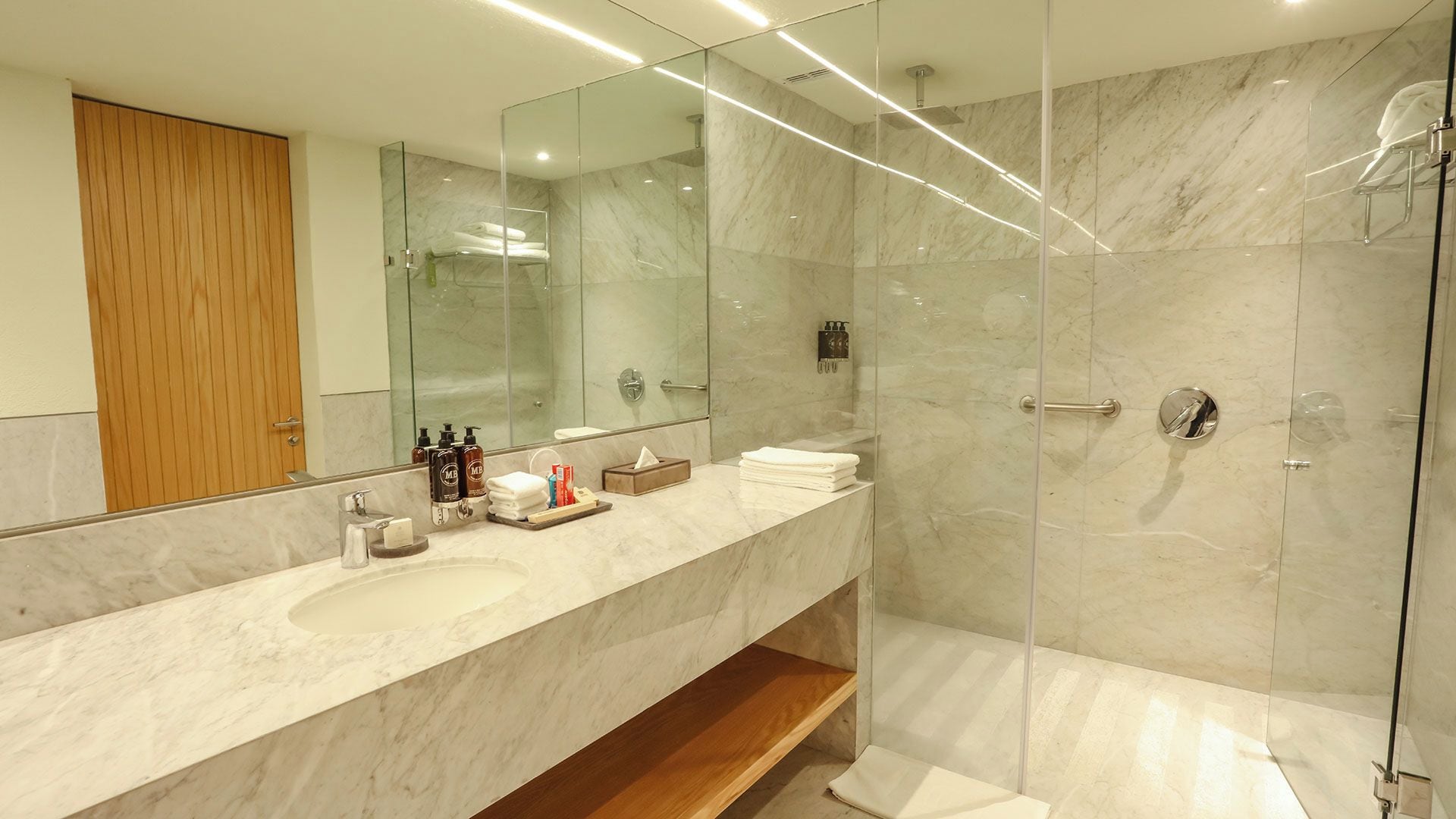 Une salle de bain moderne avec un meuble-lavabo en marbre, une cabine de douche en verre et une porte en bois.
