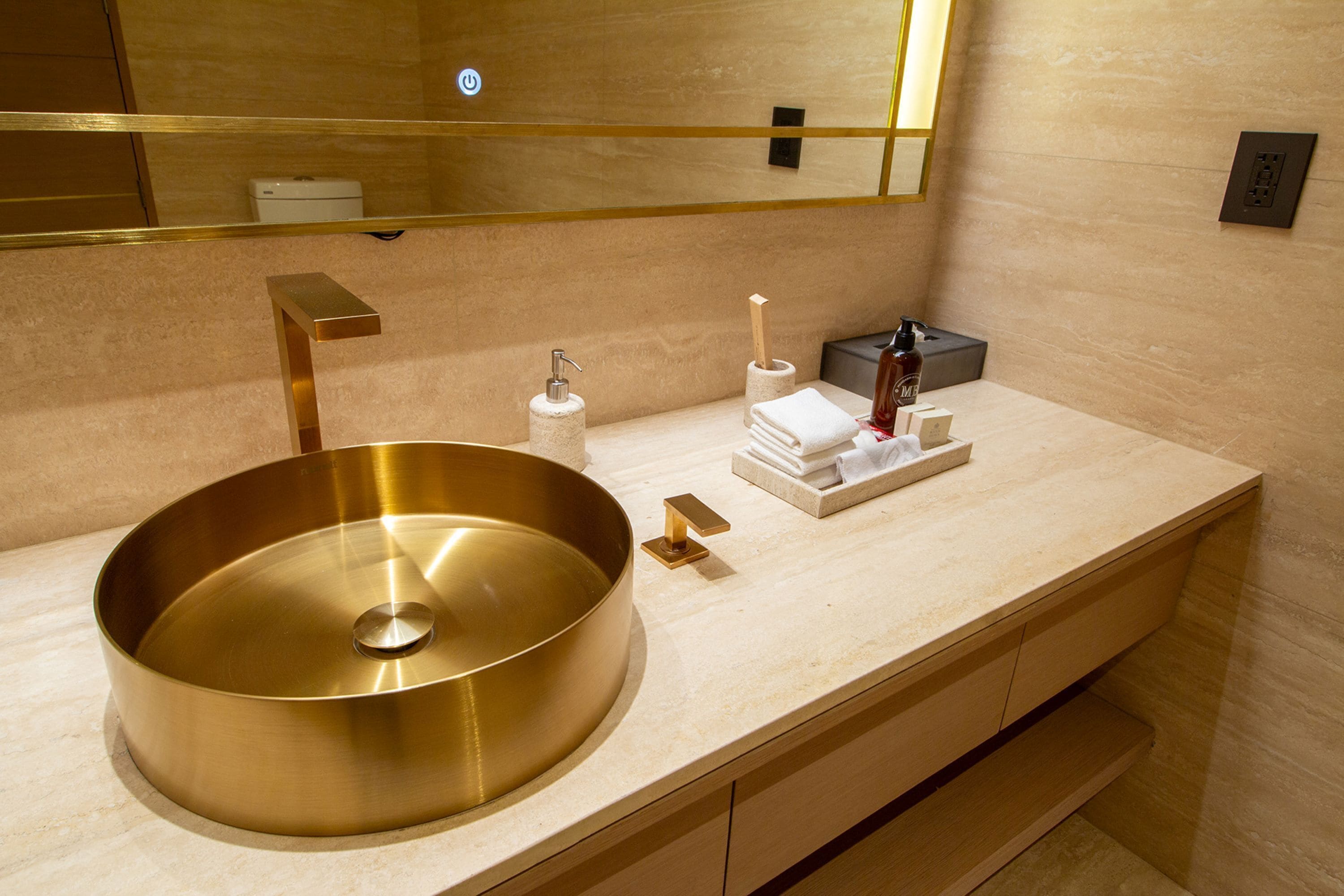 Un baño moderno con un lavamanos metálico grande y redondo, un espejo y un perchero para toallas.