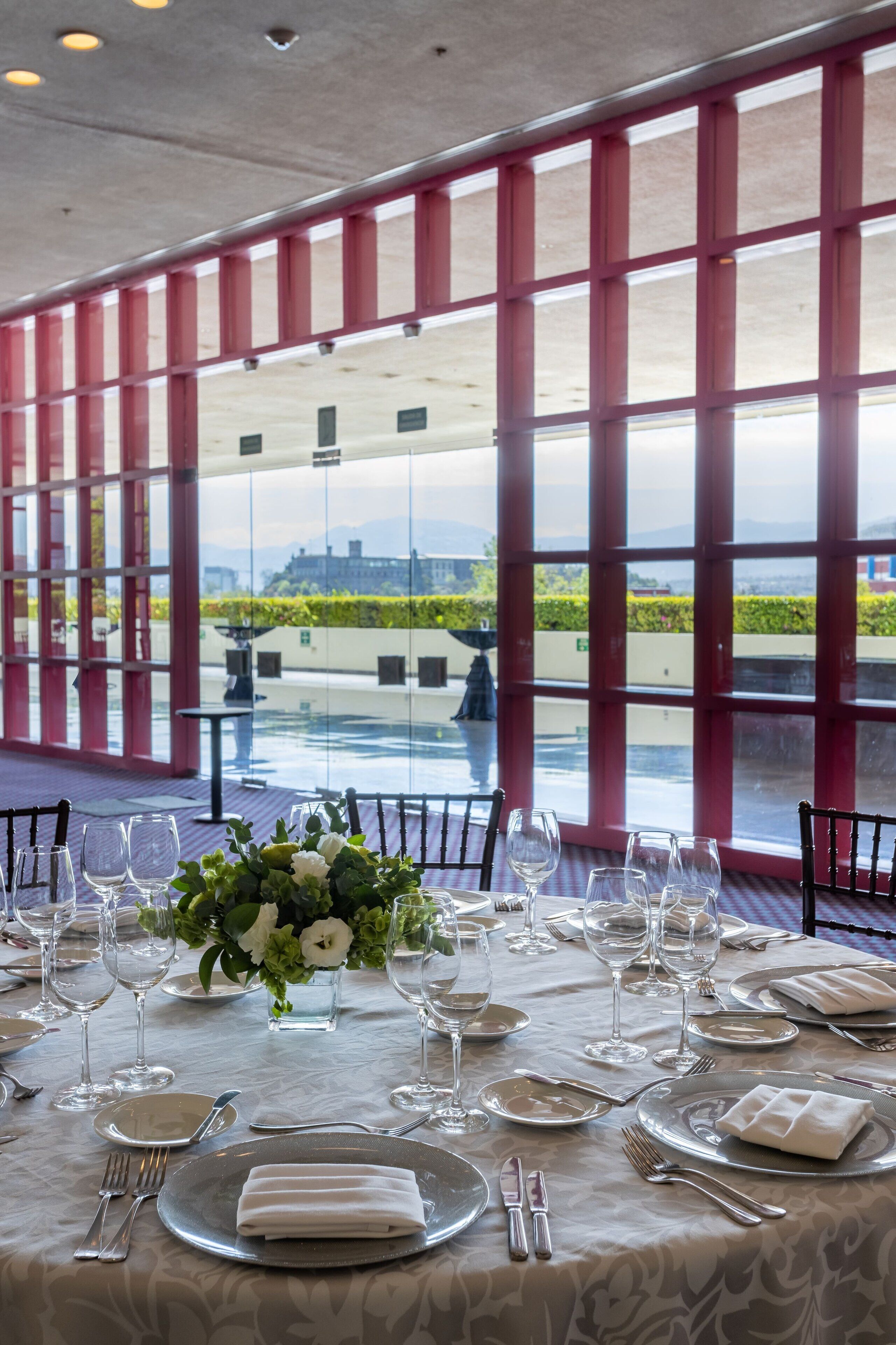 A table set for dining with a view of the outdoors through large windows.
