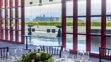 A table set for dining with a view of the outdoors through large windows.