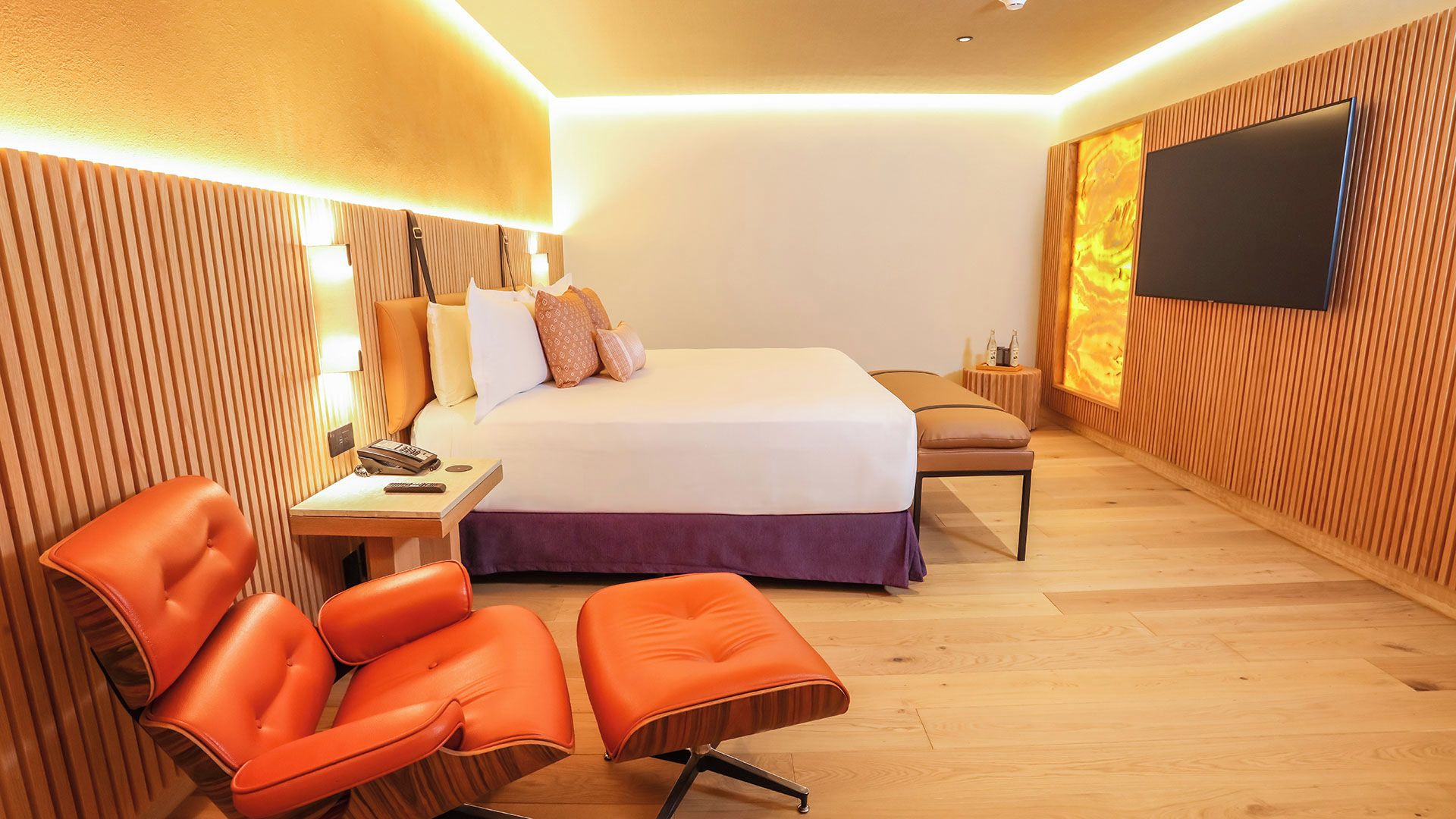 A modern hotel room with a large bed, a desk with a telephone, and a television mounted on the wall.