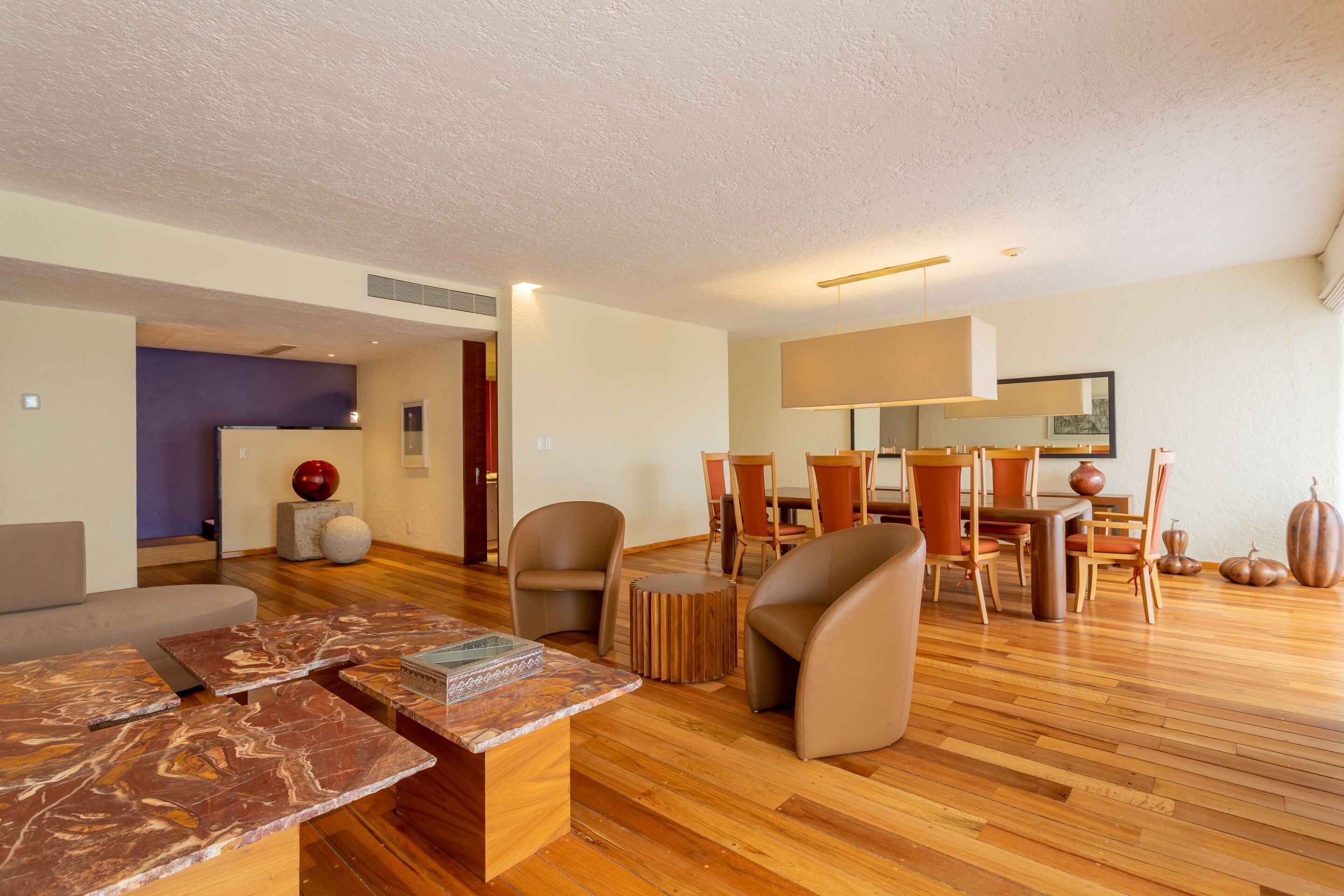 Un salon moderne avec un plancher en bois, un canapé, une table basse et un coin repas comprenant des chaises et une table.
