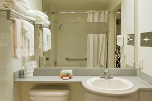 Un baño con lavabo, espejo, toallero, ducha y secador de pelo.