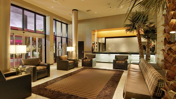 A spacious lobby with a large brown rug, multiple seating areas, and a reception desk. - Ramada Plaza by Wyndham West Hollywood Hotel & Suites (West Hollywood)