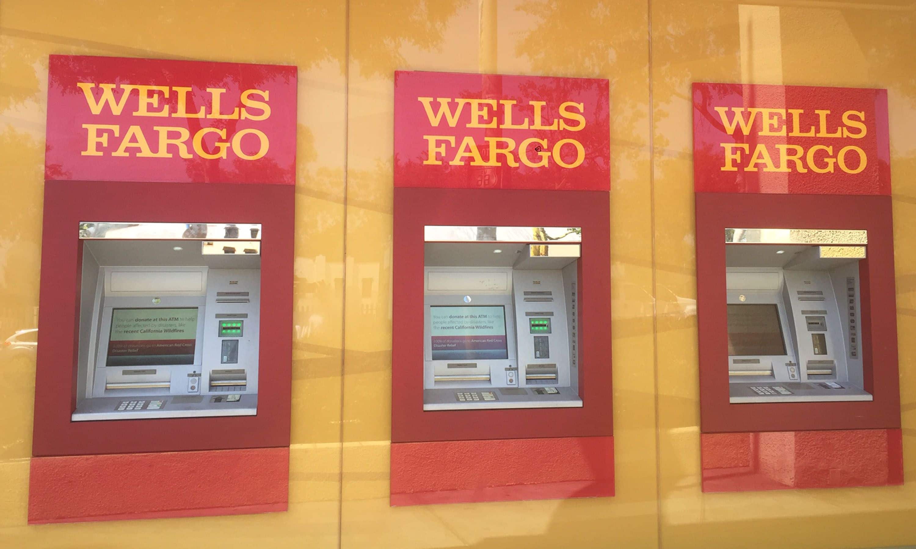 Tres cajeros automáticos de Wells Fargo con señalización roja y fondo amarillo.