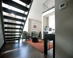 Una sala de estar moderna con una escalera, un comedor y una cocina con microondas.