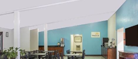 A dining area with tables and chairs, a counter with a cash register, and a television mounted on the wall.