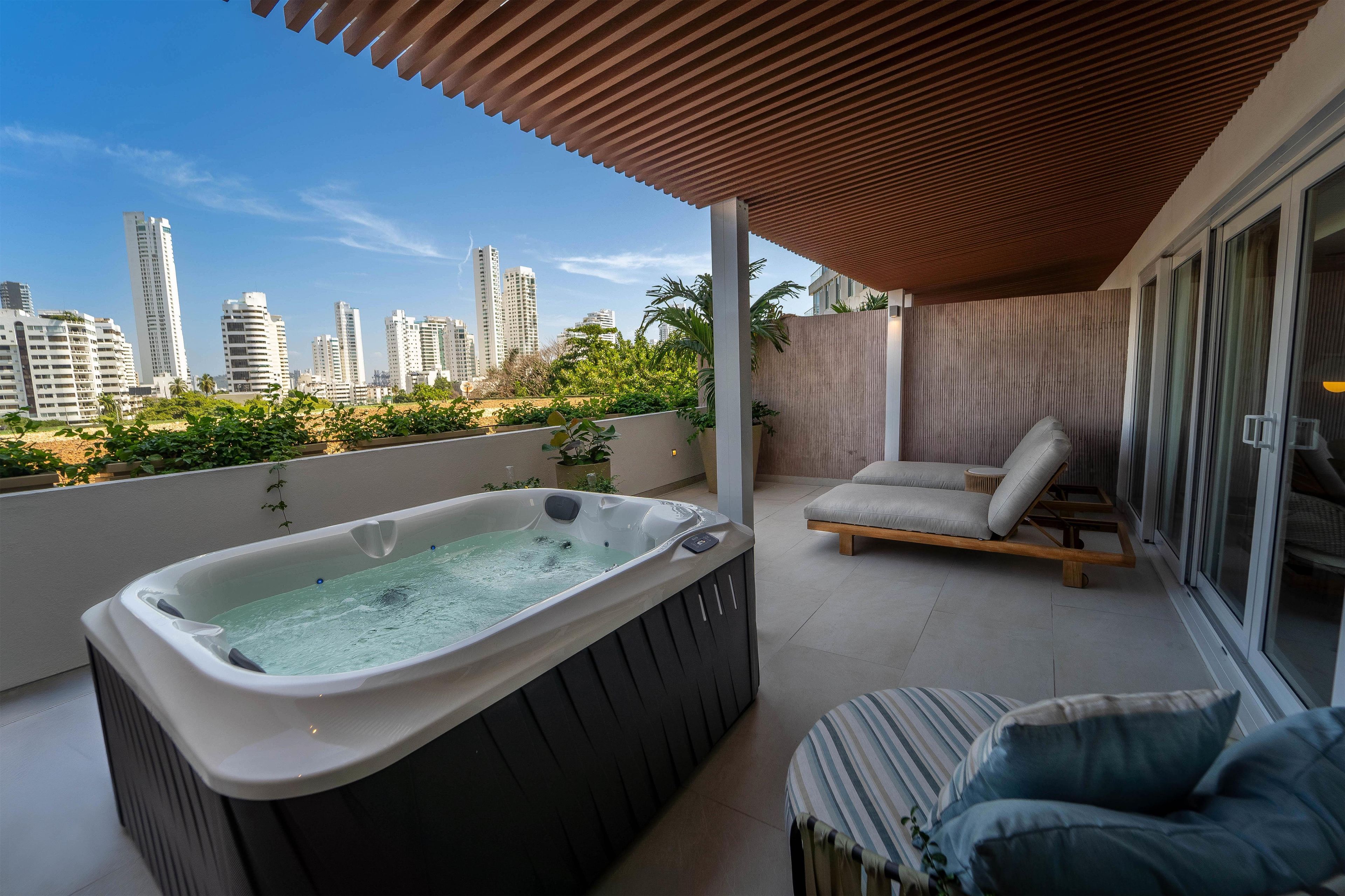 A rooftop terrace with a hot tub, lounge chair, and city skyline views.