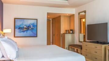 Una habitación de hotel con una cama, un cuadro, un televisor y una kitchenette.
