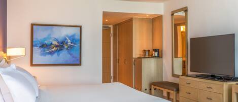 Una habitación de hotel con una cama, un cuadro, un televisor y una kitchenette.