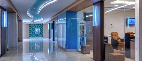 Un moderno vestíbulo de hotel con un diseño elegante, que incluye un techo curvo, una pared de cristal con un salón y una zona de recepción con asientos.