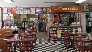 A deli counter with a checkered floor and wooden tables and chairs. - Travel Inn Hotel (New York)