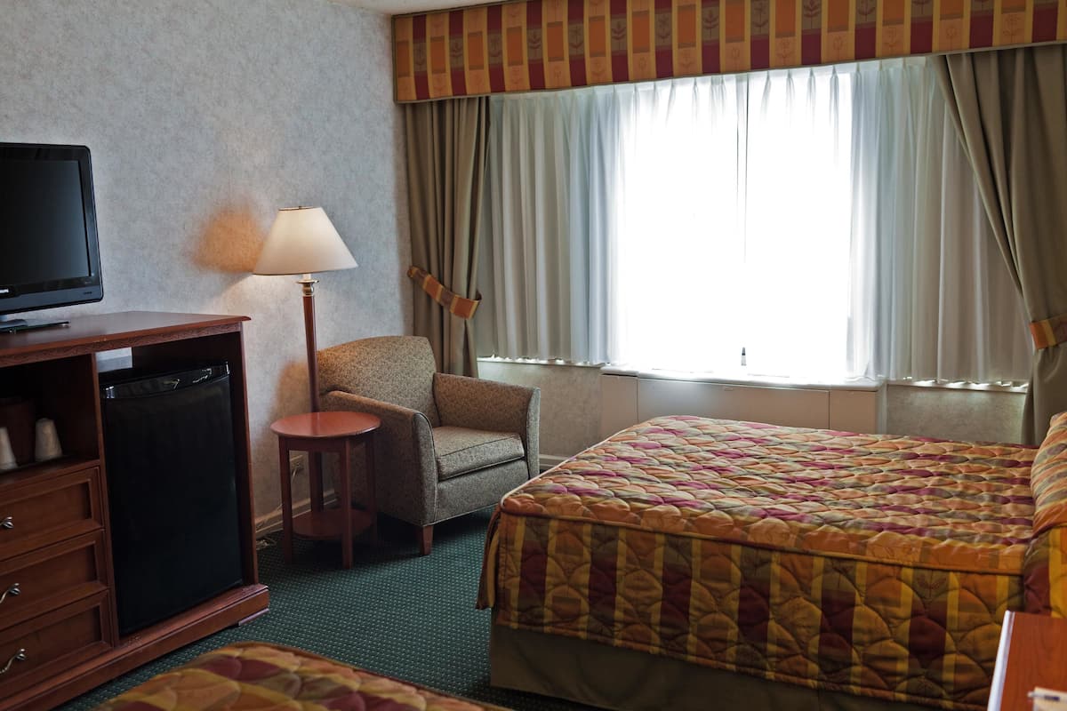 A hotel room with a bed, a chair, a television, and a small table.