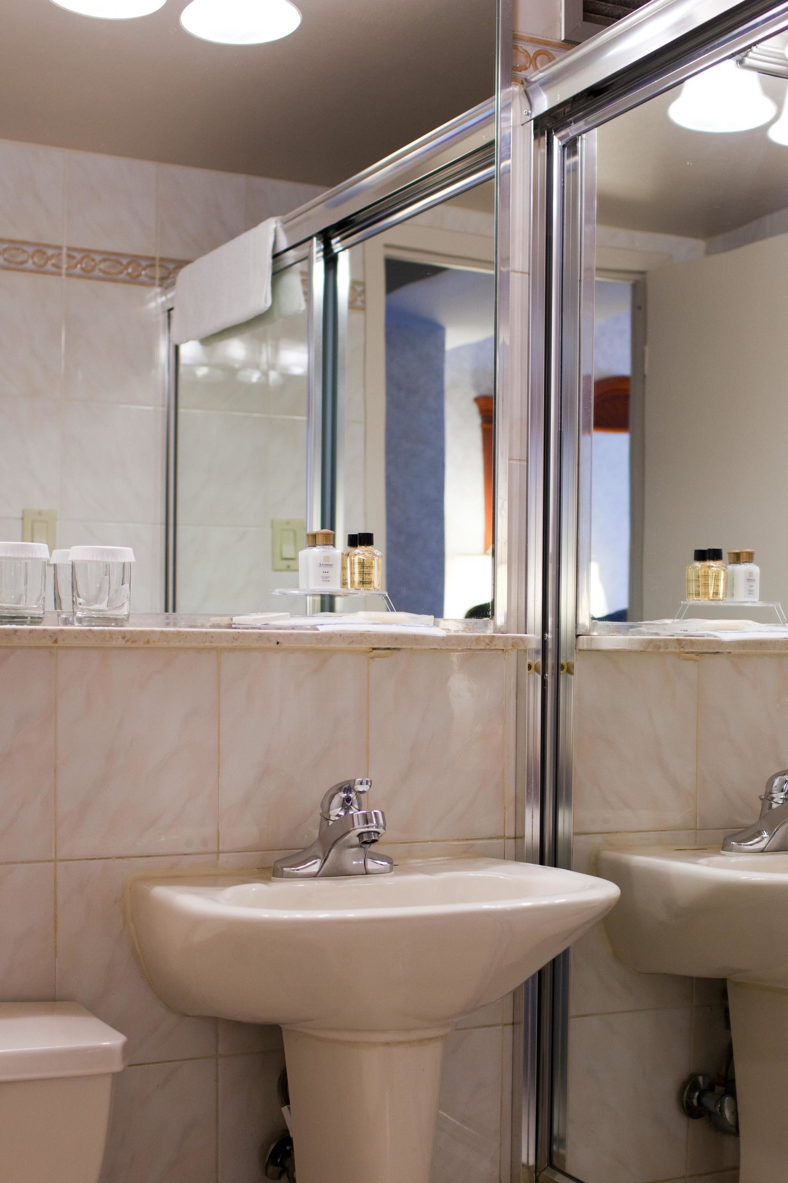 Un baño con dos lavamanos, un espejo y artículos de aseo en el mostrador.