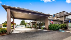 A Best Western hotel with a covered parking area, a flag, and a handicap parking sign. - Best Western Oak Meadows Inn (St. Helens)