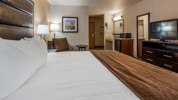 A hotel room with a large bed, a television, a desk, and a chair.