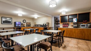 A restaurant with multiple tables and chairs, a coffee machine, a microwave, and a fruit display. - Best Western Oak Meadows Inn (St. Helens)