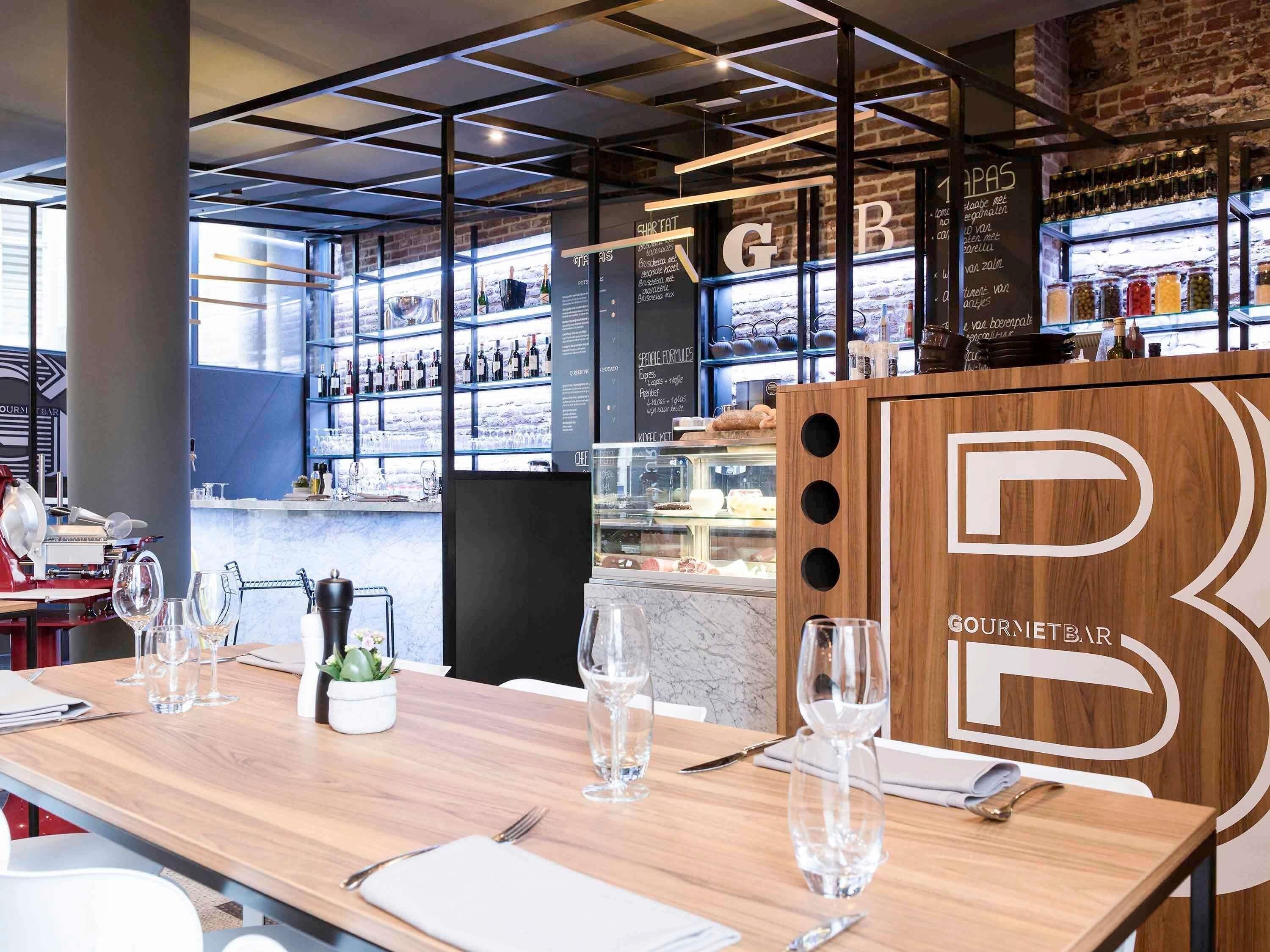 Interior de restaurante con mostrador de madera, copas de vino y una pizarra de menú.