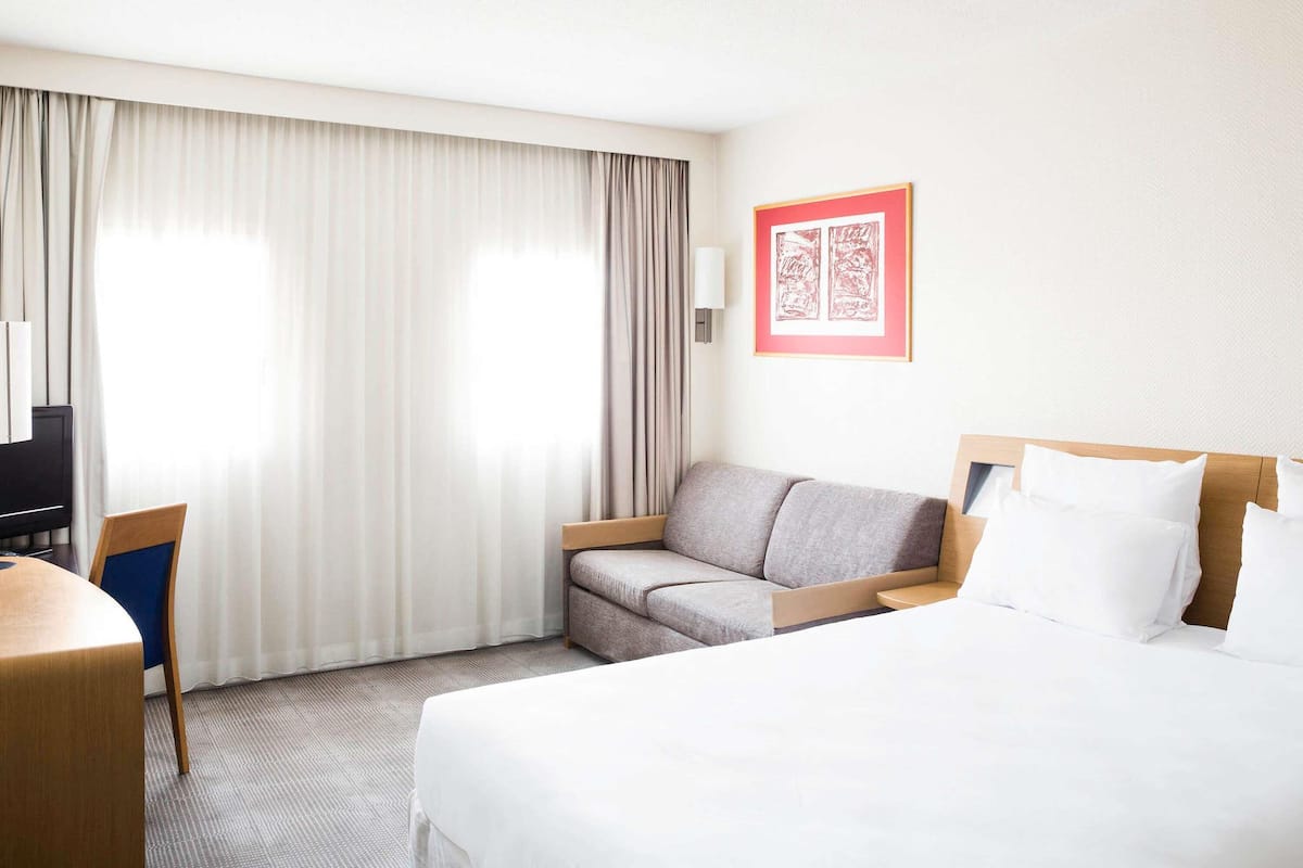 Ein Hotelzimmer mit einem Bett, einer Couch, einem Schreibtisch und einem Fernseher.