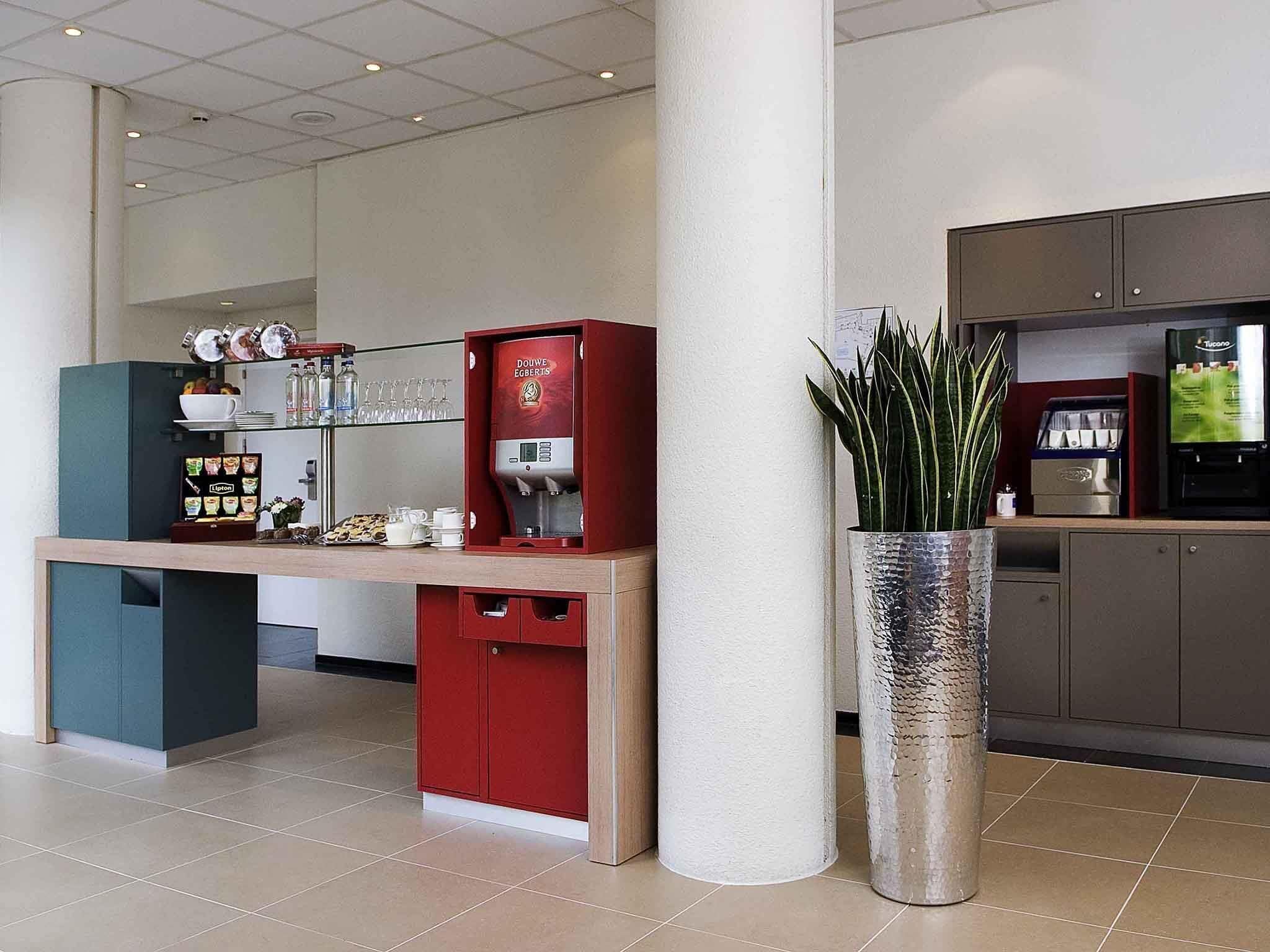 Un área de cocina moderna con cafetera, refrigerador y una planta en maceta.