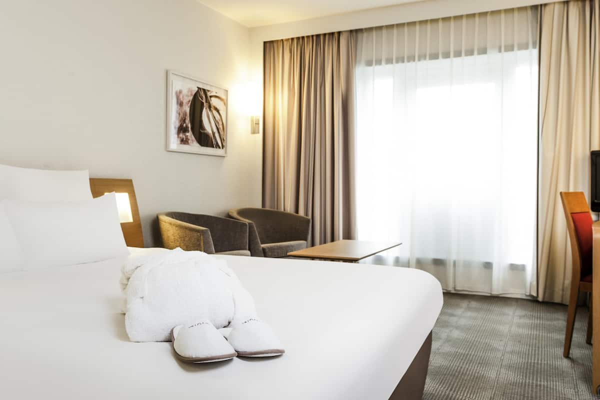 Ett hotellrum med en säng, en stol, ett bord och en tv.