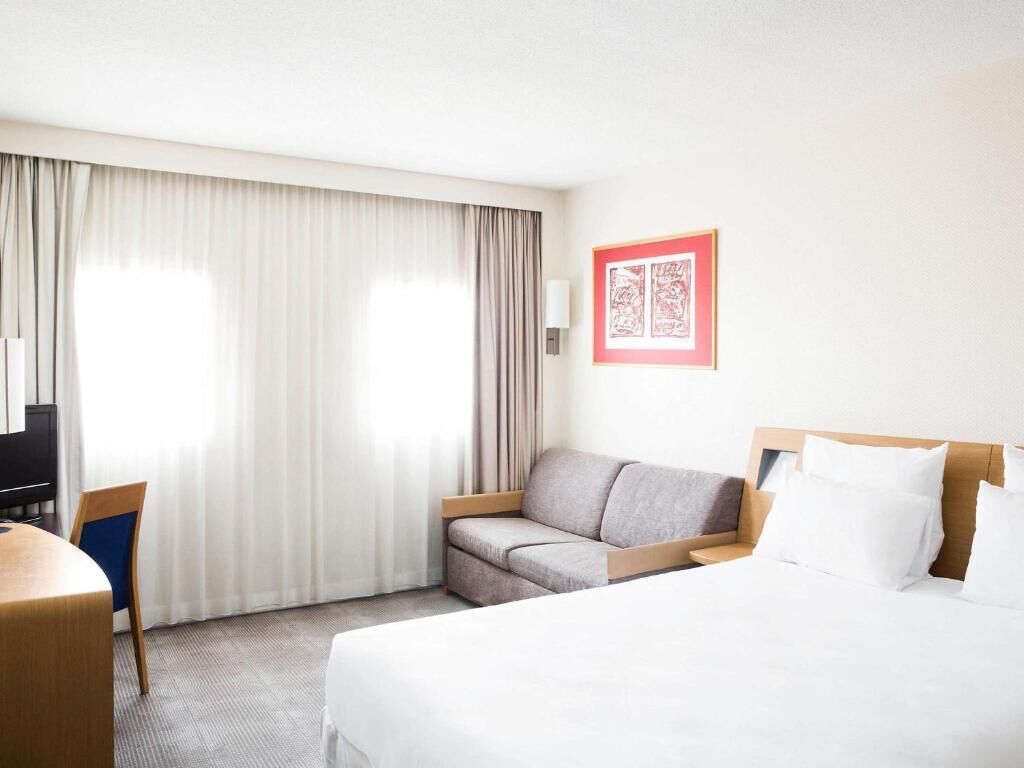 Une chambre d’hôtel avec un lit, un canapé, un bureau et une télévision.