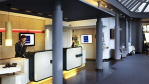 Un espace d’accueil d’hôtel au design moderne, comprenant un comptoir d’accueil, un coin salon et un mur décoratif.