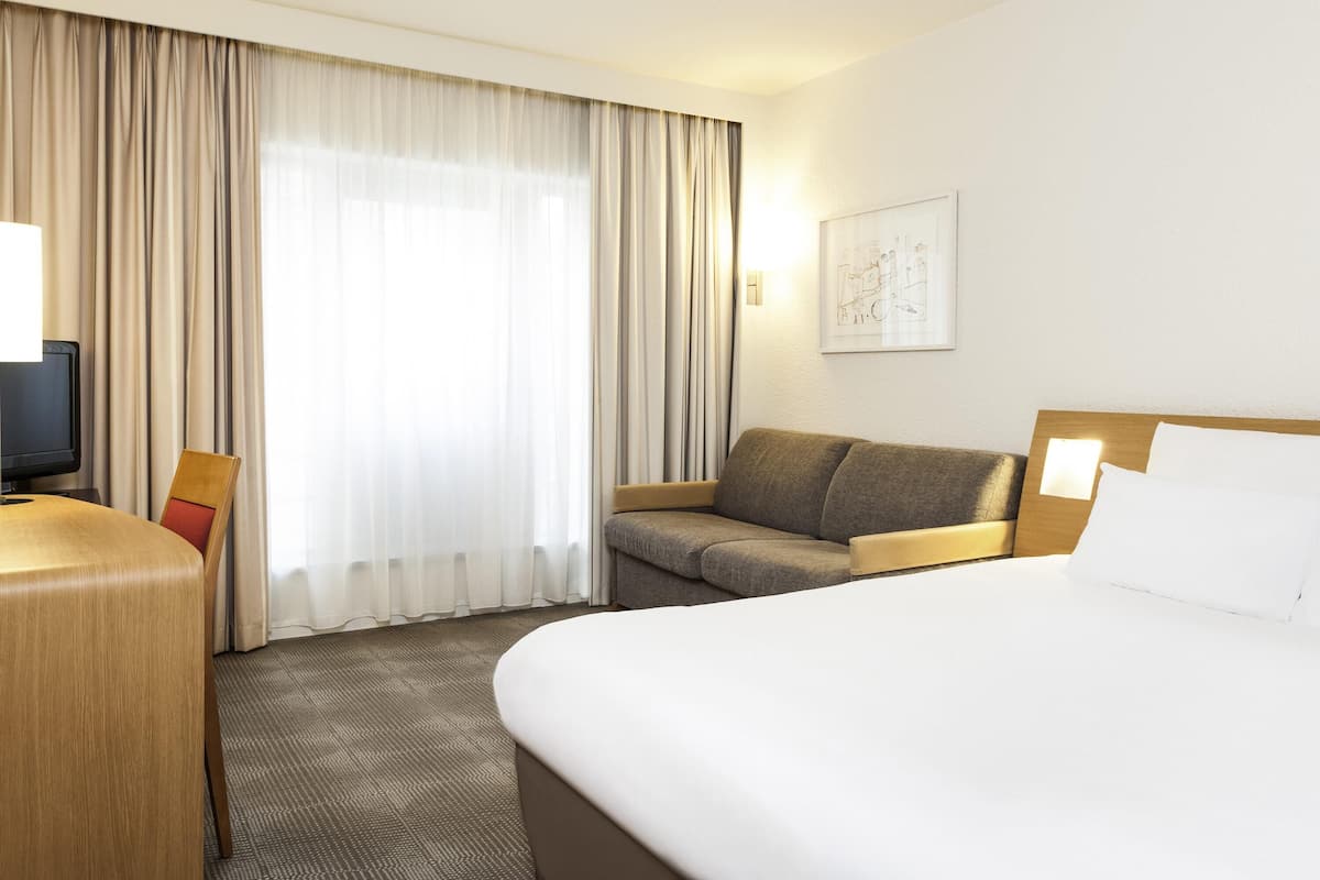 Ein Hotelzimmer mit einem Bett, einer Couch, einem Schreibtisch und einem Fernseher.