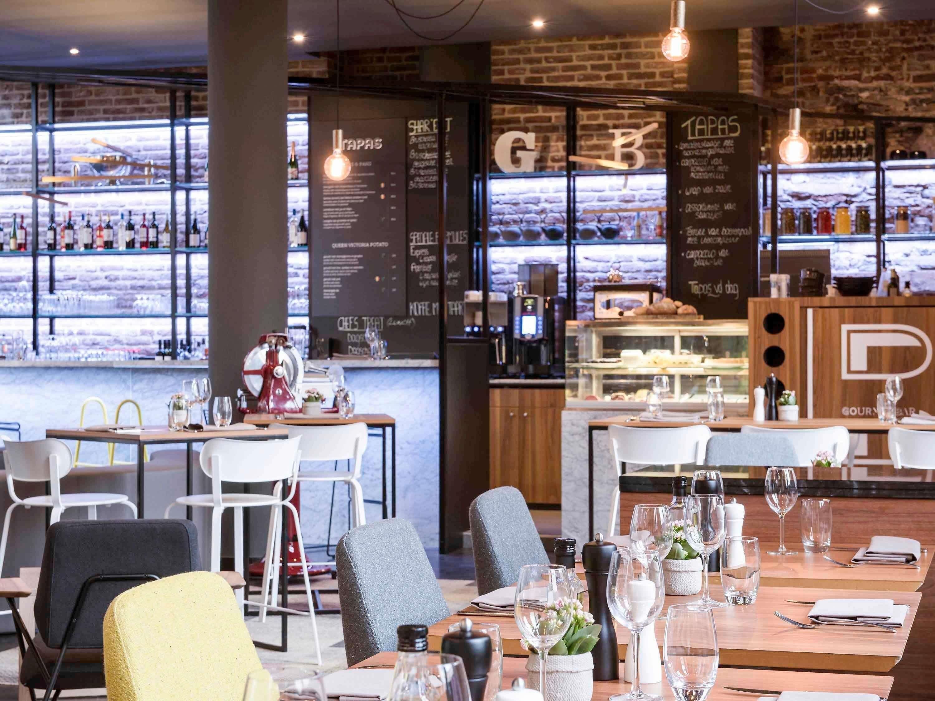A restaurant interior with tables set for dining, a bar area with bottles, and a menu board.