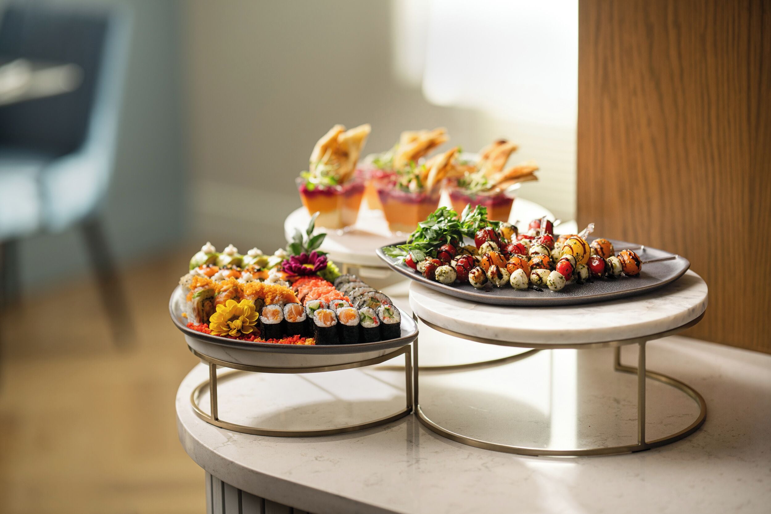 A buffet table with various dishes, including sushi and appetizers, on a marble countertop.