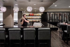 A bar area with a bartender, a bar counter, and a wall of liquor bottles. - Pomeroy Hotel & Conference Centre Grande Prairie (Grande Prairie)