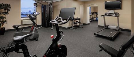 A gym with stationary bikes, treadmills, and dumbbells.