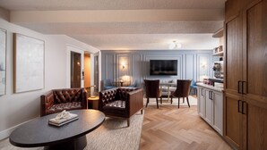 Une cuisine moderne avec des meubles en bois, un coin repas doté d’une table ronde et un espace détente comprenant un canapé et des fauteuils.