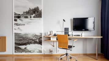 Un espacio de oficina moderno con un escritorio, una silla y un televisor de pantalla plana grande.