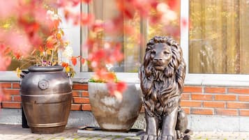 Una estatua de león y una maceta grande sobre un alféizar de ladrillo.