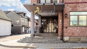 A hotel entrance with a lion emblem, a brick facade, and a clear sky. - Best Western Plus Gyldenlove Hotell (Kongsberg)